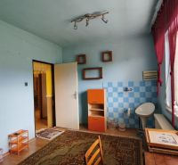 A room in a family house with tiles, a wooden-patterned floor, and a large window.