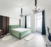 Bedroom in a 3-room apartment with a green bed and chandeliers, floor with wooden decor.