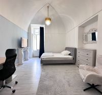 Bright bedroom with a desk, bed, wardrobe, and window, wooden decor flooring.