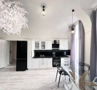 A kitchen in a 3-room apartment with white cabinets, black appliances, and a wood-patterned floor.