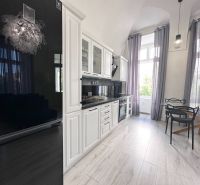 A spacious kitchen with white furniture and a floor with a wood decor in a 3-room apartment.