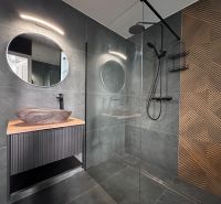 A bathroom in a 3-room apartment with a round mirror and a decorative wall.