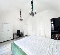 A bedroom with chandeliers and a desk in a three-room apartment with white wardrobes.