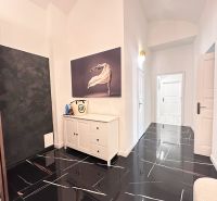 A hallway in a 3-room apartment with a dark floor and white furniture.
