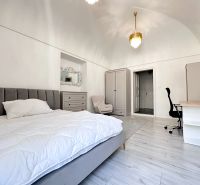 A bedroom in a 3-room apartment with wood-patterned flooring and stylish lighting.