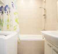 Bathroom with a bathtub, washing machine, and curtain in a 3-room apartment.
