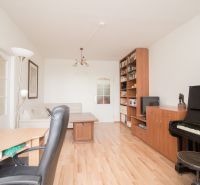 Living room in a 3-room apartment with a piano and a wooden decor floor.