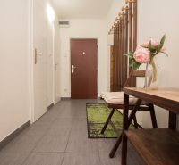 Entrance hall with decoration and hooks in a 3-room apartment, gray tiles on the floor.