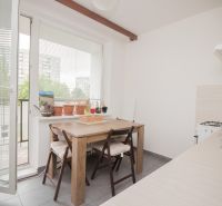 The kitchen in a 3-room apartment with a wooden table, large windows, and a balcony.