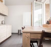 A kitchen in a 3-room apartment with a wooden decor, a table, and a view outside.