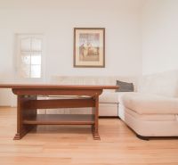 Living room with a corner sofa, table, and floor with wood decor in a 3-room apartment.
