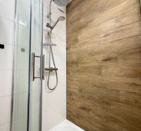 Shower corner with a floor with a wooden decor in a studio apartment.