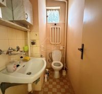 A bathroom in a family house with a sink and a toilet, beige tiles and flooring.
