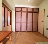 Interior of a family house with a brown cabinet and table, floor with wooden decor.