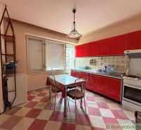 A kitchen in a family house with red cabinets and a checkered floor.