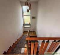 A staircase with a wooden railing and a window in a family house, flooring with a wooden decor.