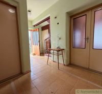 The hallway of a family house with simple furniture and light-colored doors.
