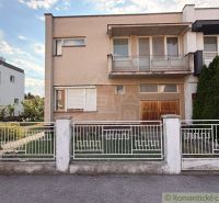 A family house in Nové Zámky with a balcony and a garden, enclosed by a white fence.