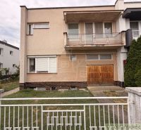 A family house in Nové Zámky with an old garage and a balcony, enclosed by a metal fence.