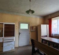 A kitchen in a family house with wooden furniture, a large window, and older equipment.