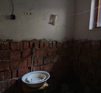 Incomplete bathroom in a family house with exposed bricks and a sink.