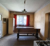 A kitchen in a family house with a dining table, a stove, and red curtains.