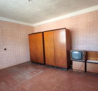 A room in a family house with wallpaper, wardrobes, and an old television.
