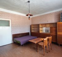 A room in a family house with wooden furniture, a bed, a table, and a stove.