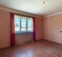 A room with patterned wallpaper and a wooden decor floor in a family house.