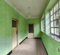 A hallway in a family house with large windows and green walls.