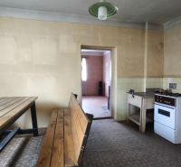 A kitchen in a family house with a dining table, a gas stove, and tiled flooring.