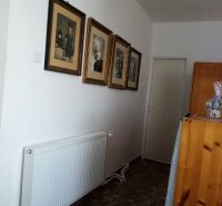 A hallway in a family house with photographs and a radiator, tiled floor.