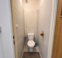 A toilet with tiles in a 3-room apartment, light tiles, white sanitary ware.