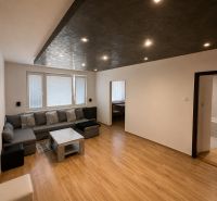 Living room in a three-room apartment with a wooden decor floor and seating.