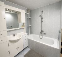 A bathroom in a 3-room apartment with a corner bathtub and white sink furniture.
