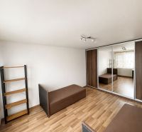 A bedroom in a 3-room apartment with a wooden decor floor, a mirrored wardrobe, and sofas.
