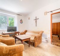 Living room in a family house with older sofas, a television, and a wooden decor floor.