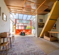 A family house with glass doors, a chair, a table, and a carpet on a floor with a wooden decor.
