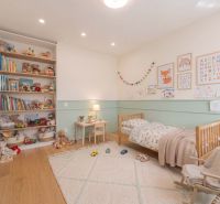 Children's room in a family house with a bed, chair, shelf, and floor with a wooden decor.