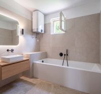 Bathroom with a bathtub and a sink in a family house with a wooden decor floor.