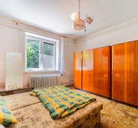 Bedroom in a family house with beds, a wooden wardrobe, and a radiator by the window.