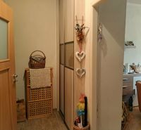 In the 2-room apartment, there is a wooden decor, a basket, decorations, and a view of the kitchen.