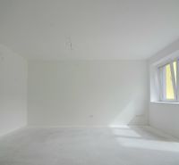 A bright room in a 3-room apartment with a large window and white walls.