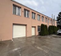 Warehouses and halls in Veľký Šariš with a concrete access road and garage doors.