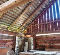 Interior of a wooden structure from Pozemkov - living with a sloped roof and rock wall.