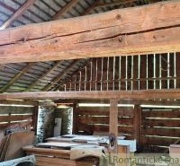 The interior of a wooden barn with thick beams and stored materials. Land - housing.