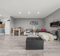 Living room with wood-patterned flooring, a sofa, and a dining table in a family house.