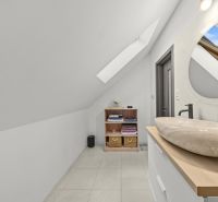 A bathroom with a window in the attic of a family house and with a modern sink.