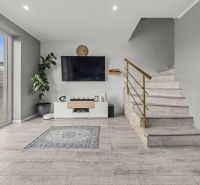 Living room of a family house with a wooden decor floor, a television, and a staircase.