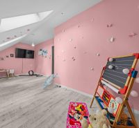 A children's room in a family house with pink walls and a wooden decor floor.